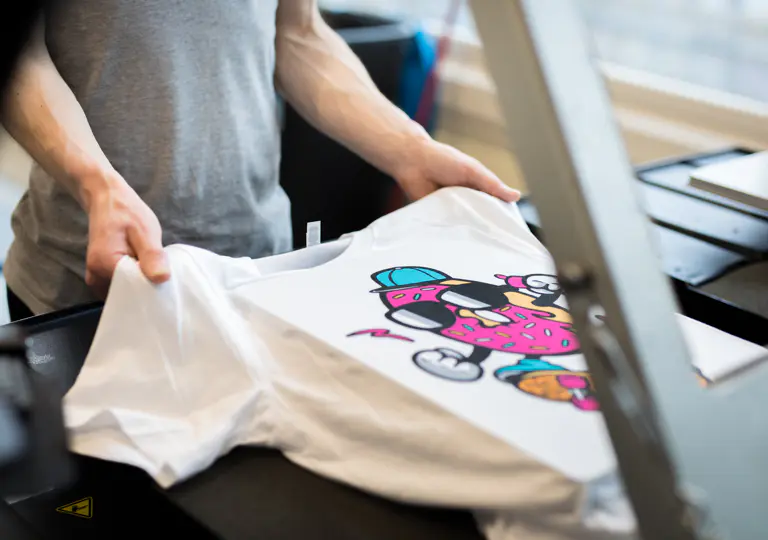 T-Shirt mit farbigem Textildruck wird in unserer Produktion aus der Transferpresse genommen